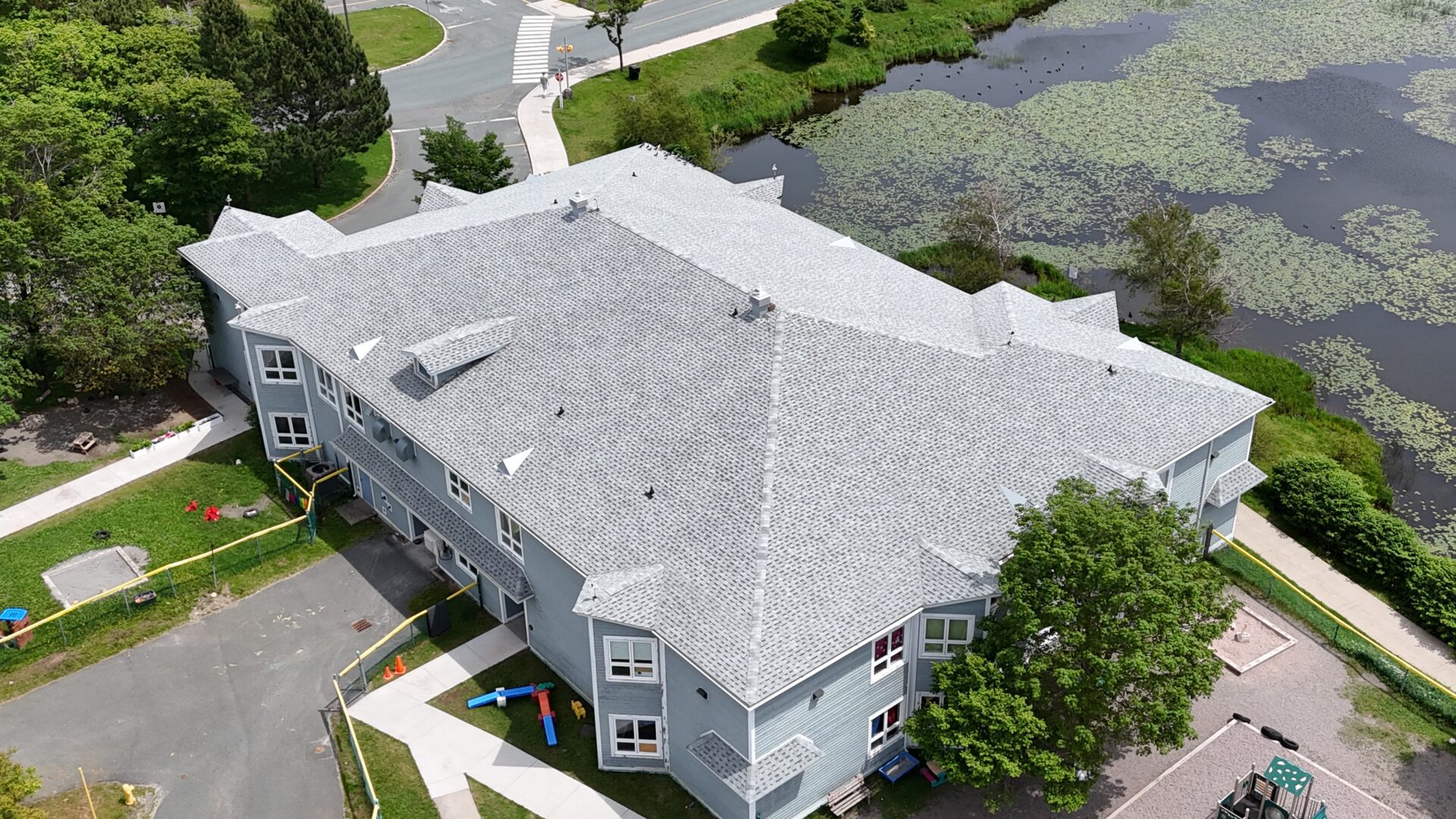 Aerial view of a gray multi-story building with a shingled roof Aerial view of a gray multi-story building with a shingled roof