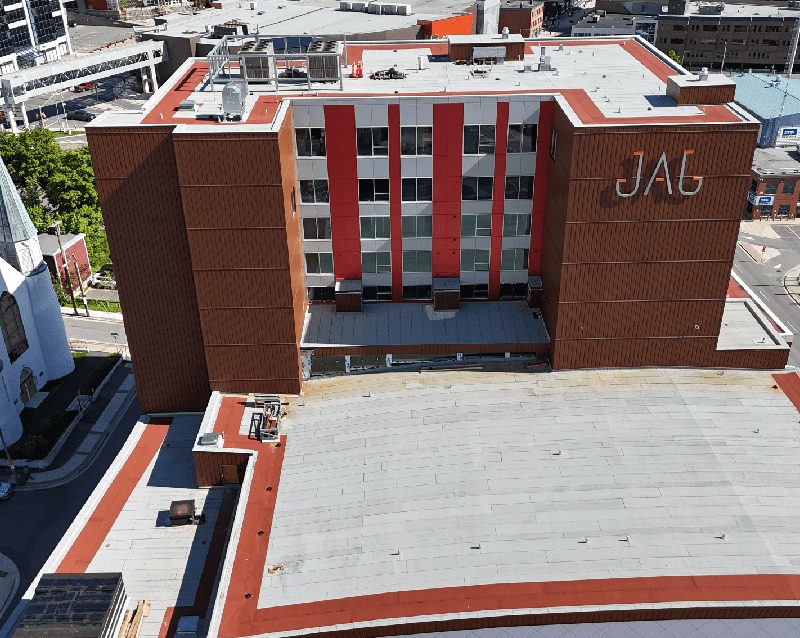 Aerial view of a multi-story building with "JAG" on the facade, featuring red and white vertical stripes