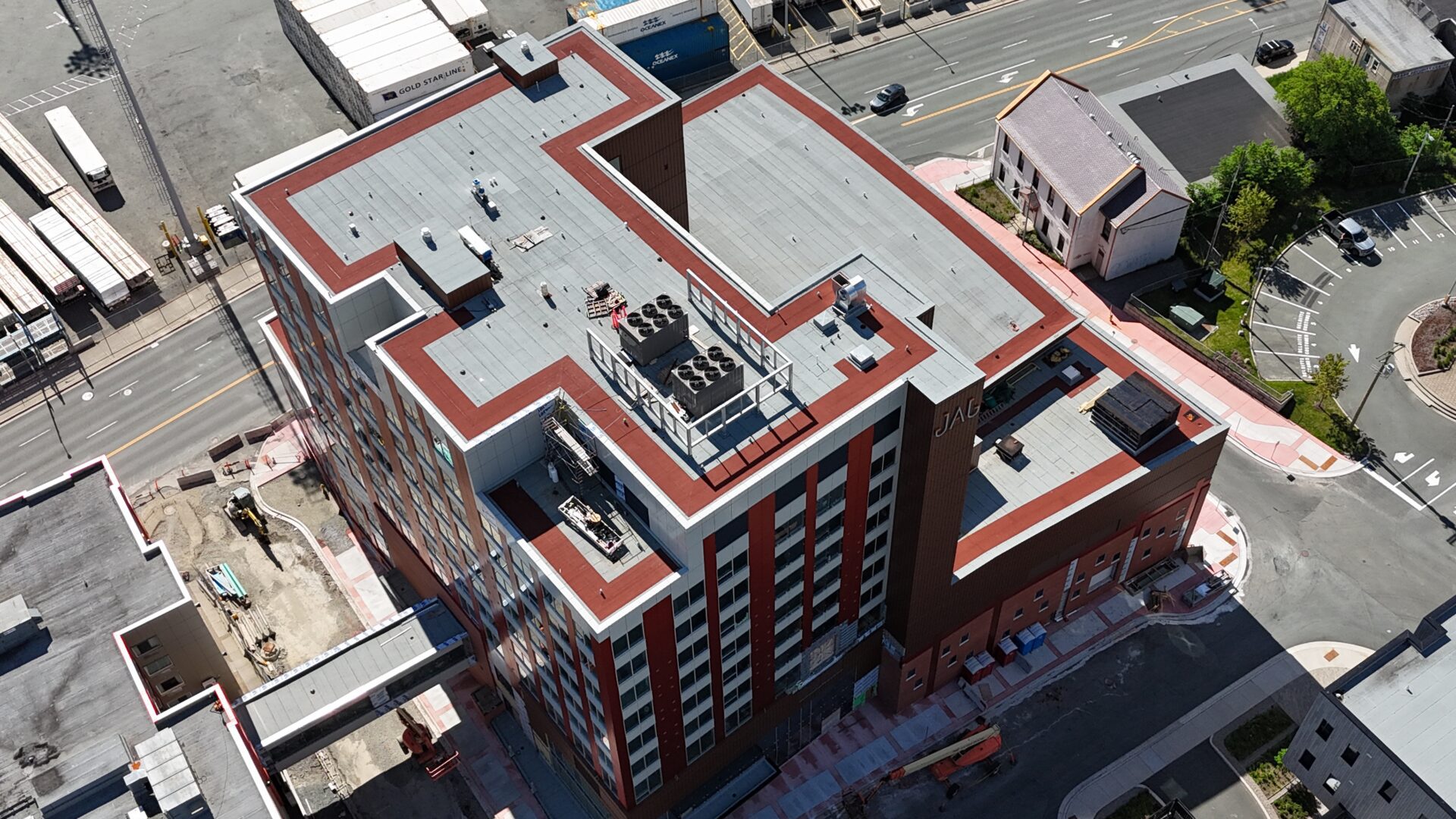 Aerial view of a multi-story building with "JAG" on the facade, featuring red and white vertical stripes