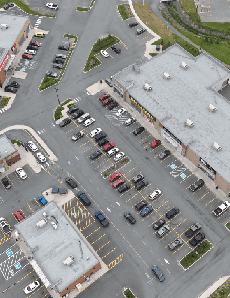 Aerial view of a commercial area with parking, a roundabout, and several buildings